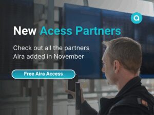 A man holds up his phone in front of a row of airport flight screens. Text: "New Access Partners: Check out all the partners Aira added in November." Aira logo at top right.
